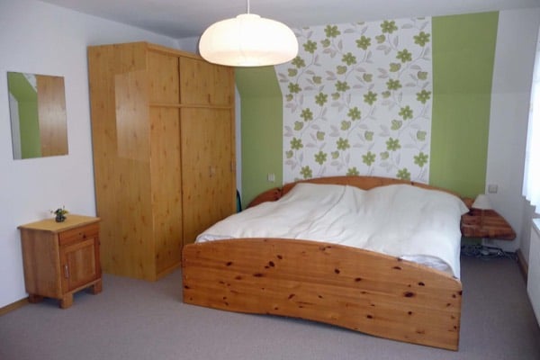Schlafzimmer mit Holzdoppelbett, Kleiderschrank und Nachttisch