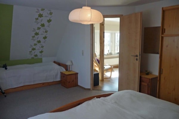 Zwei Einzelbetten im Schlafzimmer mit offener Tür zum Wohnraum